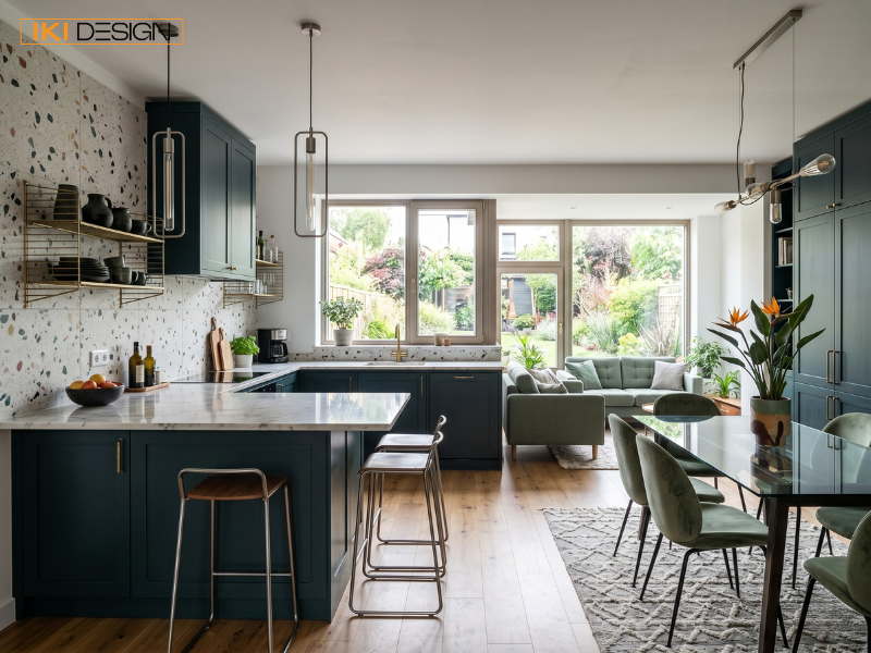 Căn bếp hiện đại có hệ tủ xanh, tường terrazzo và bàn ăn tinh tế hướng ra sân vườn xanh mát